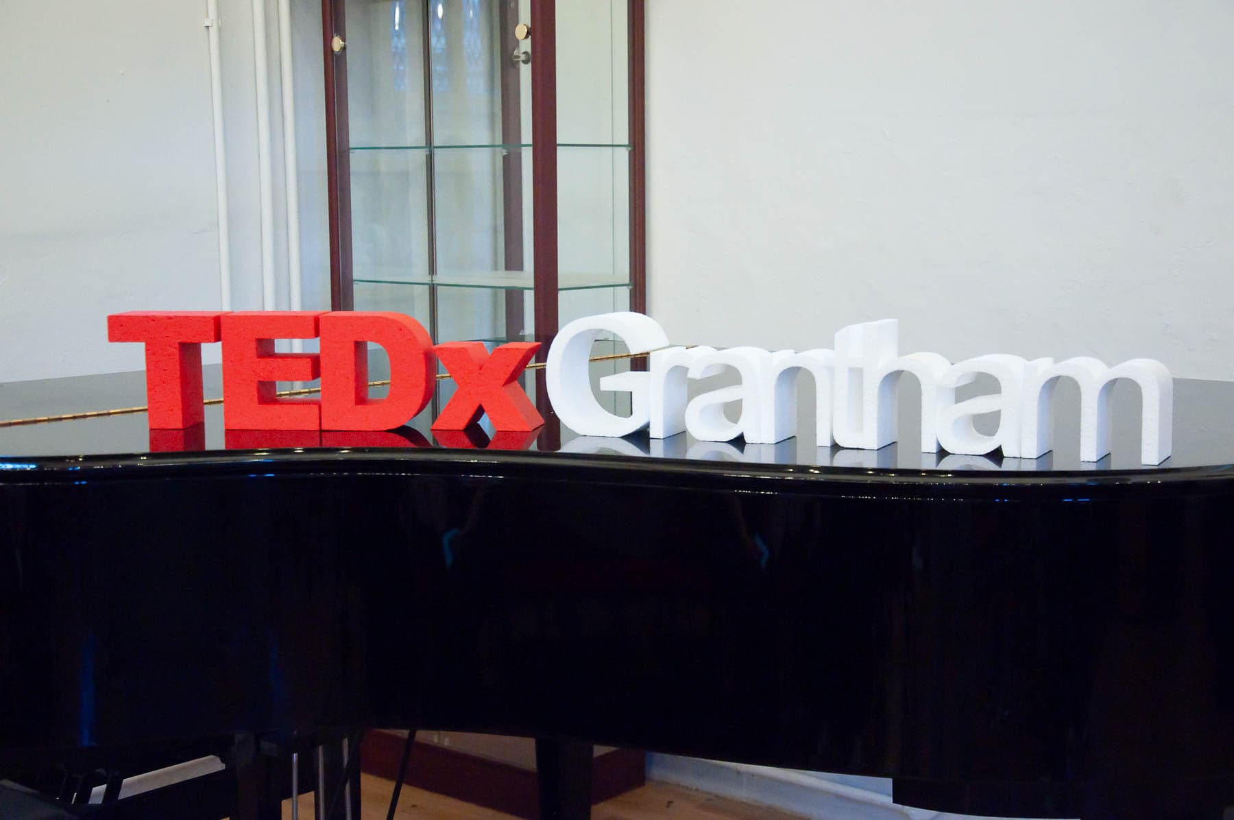 Red and white TEDxGrantham letters on the piano